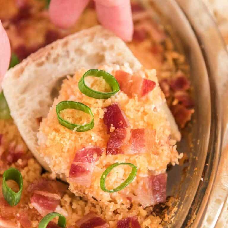 hand holding cracker with Charleston cheese dip and green onion