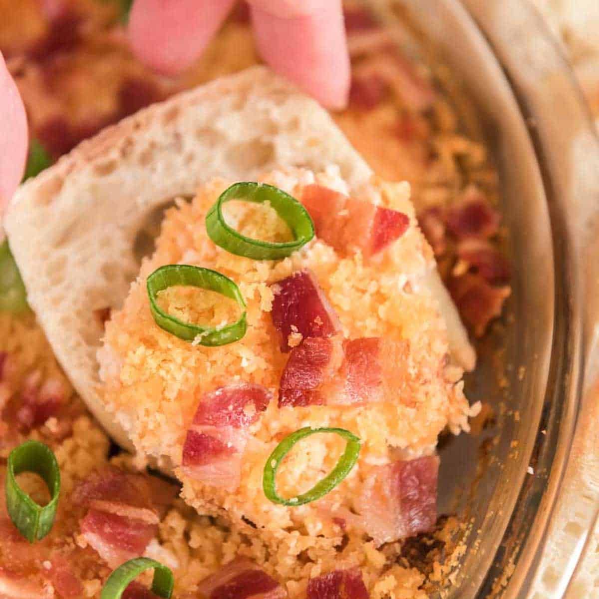 hand holding cracker with Charleston cheese dip and green onion
