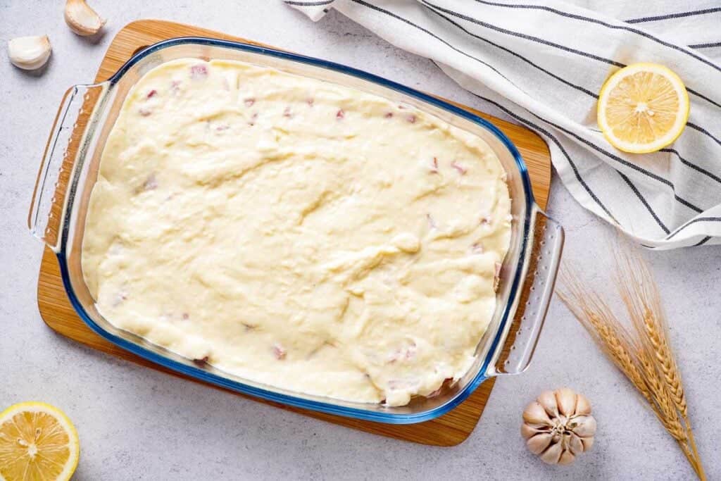 swiss cheese sauce covering chicken and ham in glass casserole dish