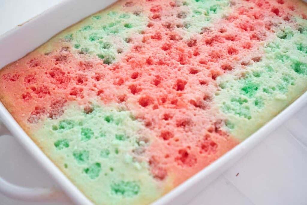 cake with holes poked in the top and red and green jello poured over it