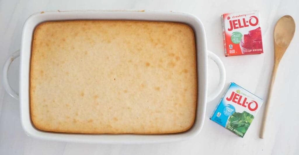 cake in white dish with two boxes of jello nearby