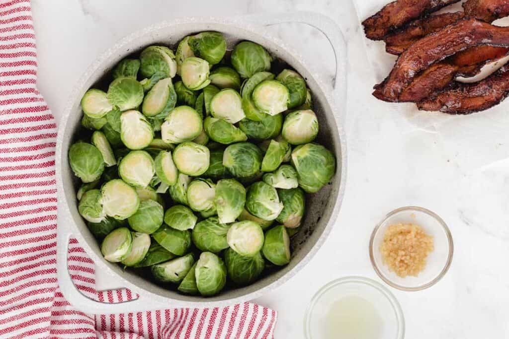 brussel sprouts in dutch oven before cooking with bacon to the side