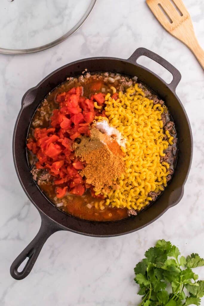 skillet with all ingredients for taco mac and cheese in it