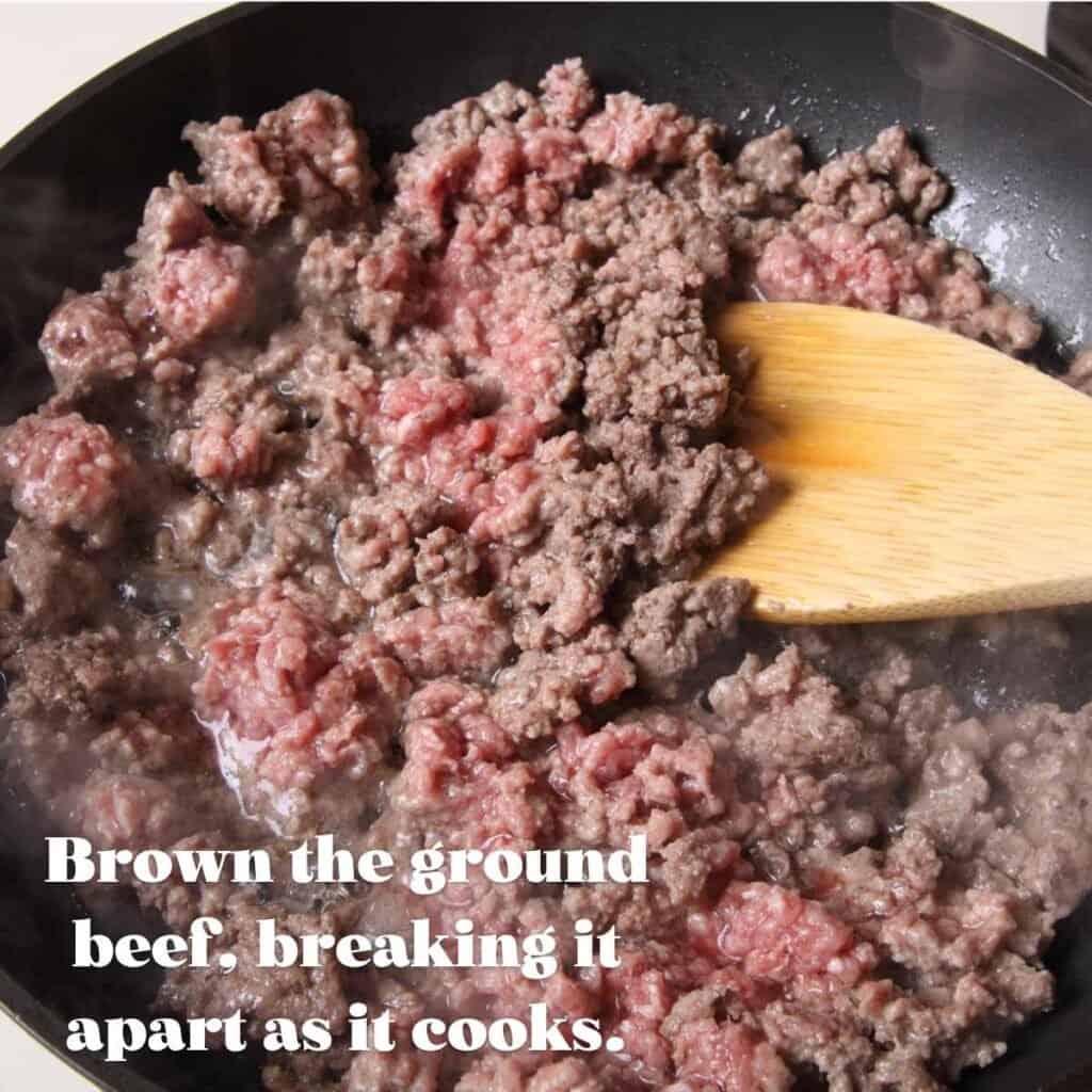 cooking ground beef in a black skillet with wooden spoon