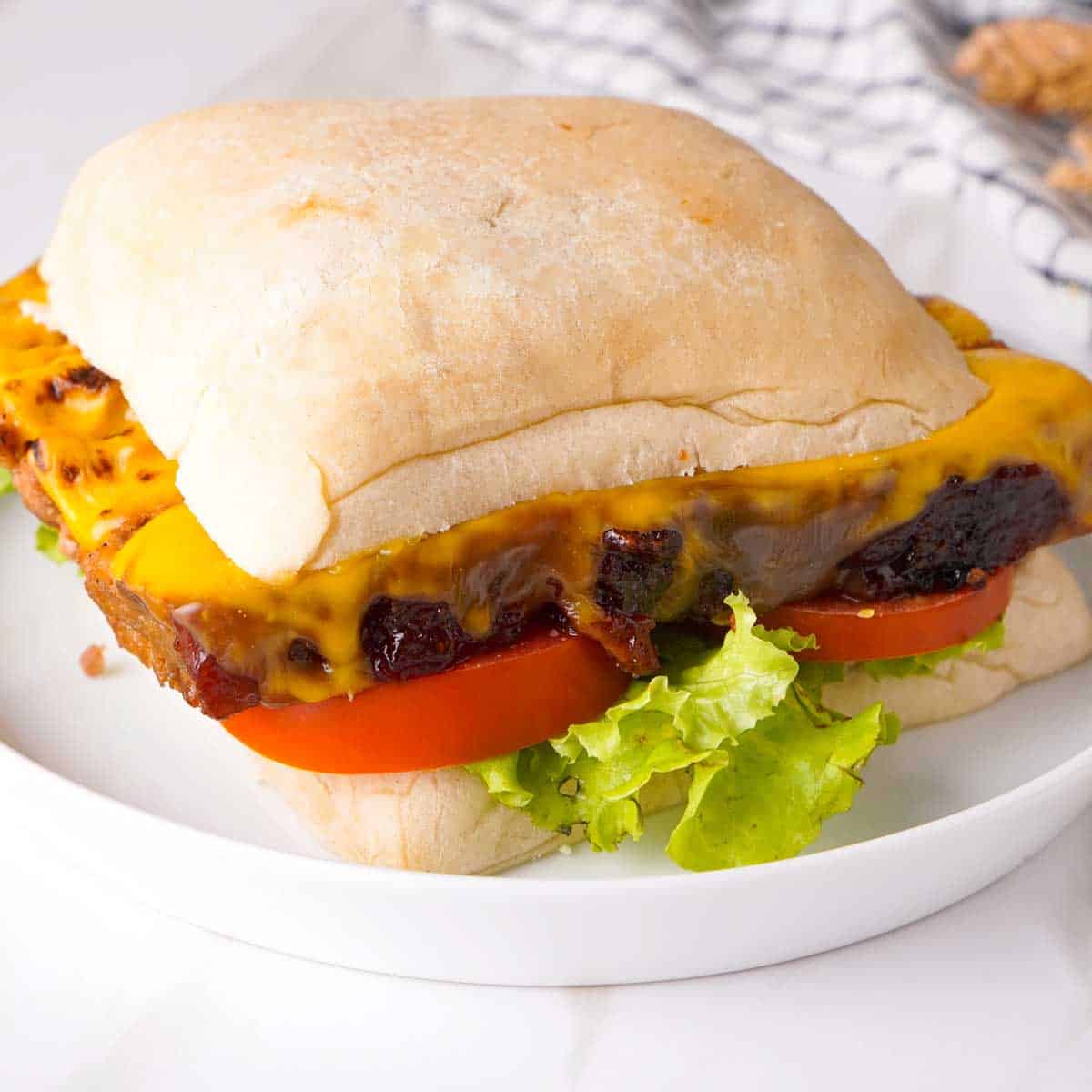 meatloaf sandwich with lettuce, tomato, and cheese on ciabatta bread