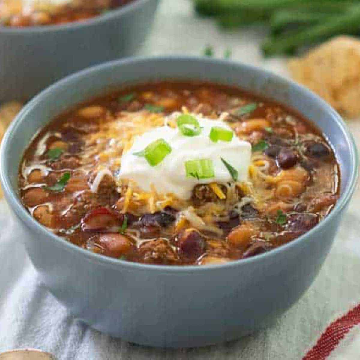 taco soup in a light blue bowl topped with sour cream and chopped green onion