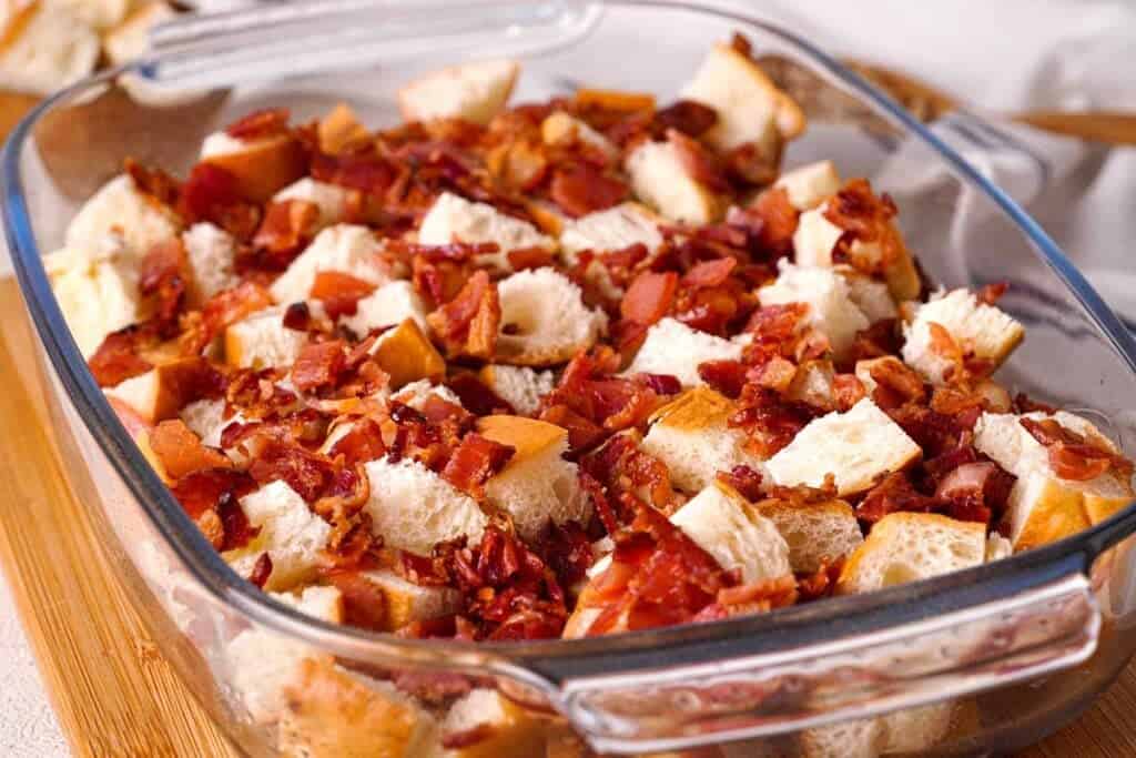 bagel pieces and chopped bacon in glass casserole dish