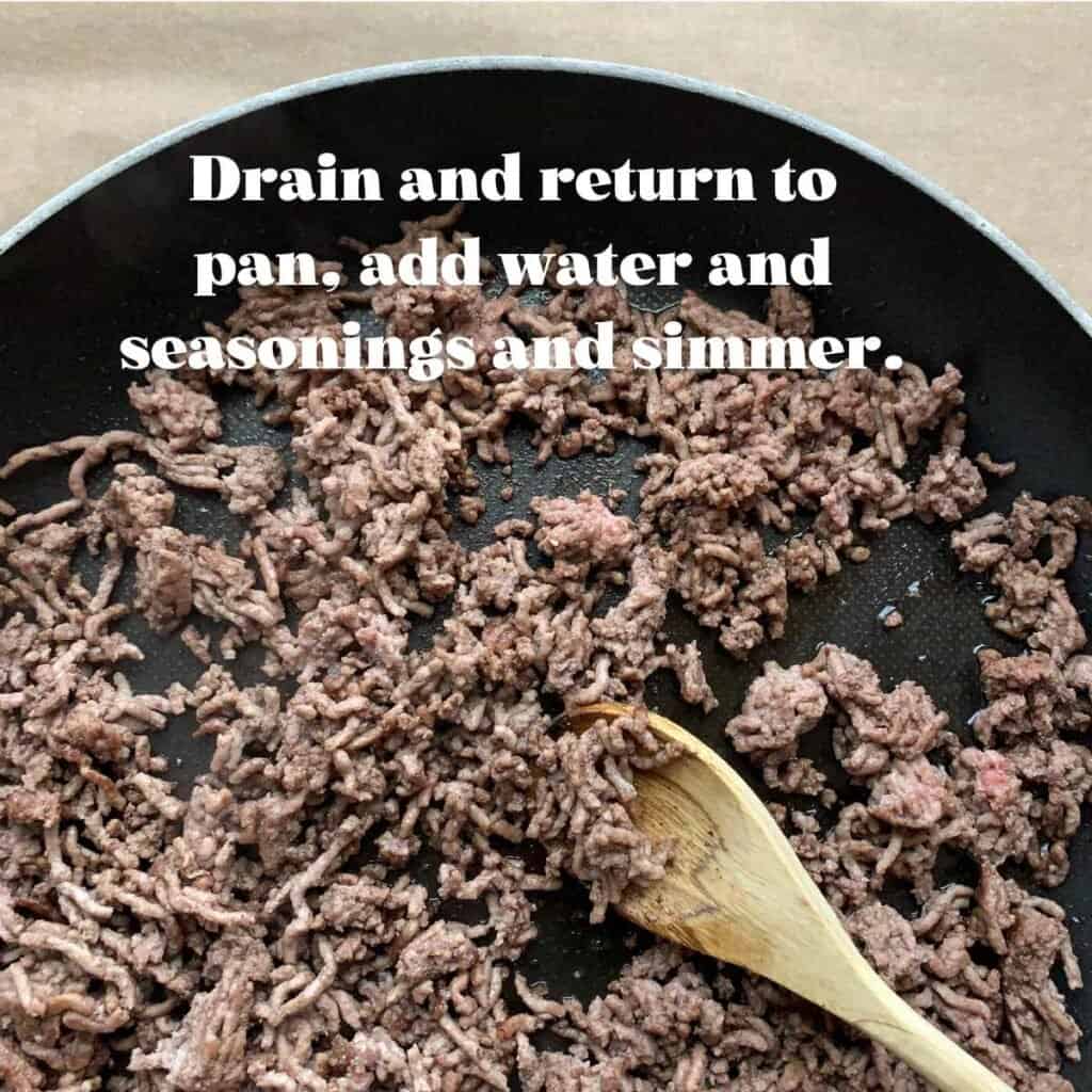 wooden spoon stirring cooked ground beef in a black skillet