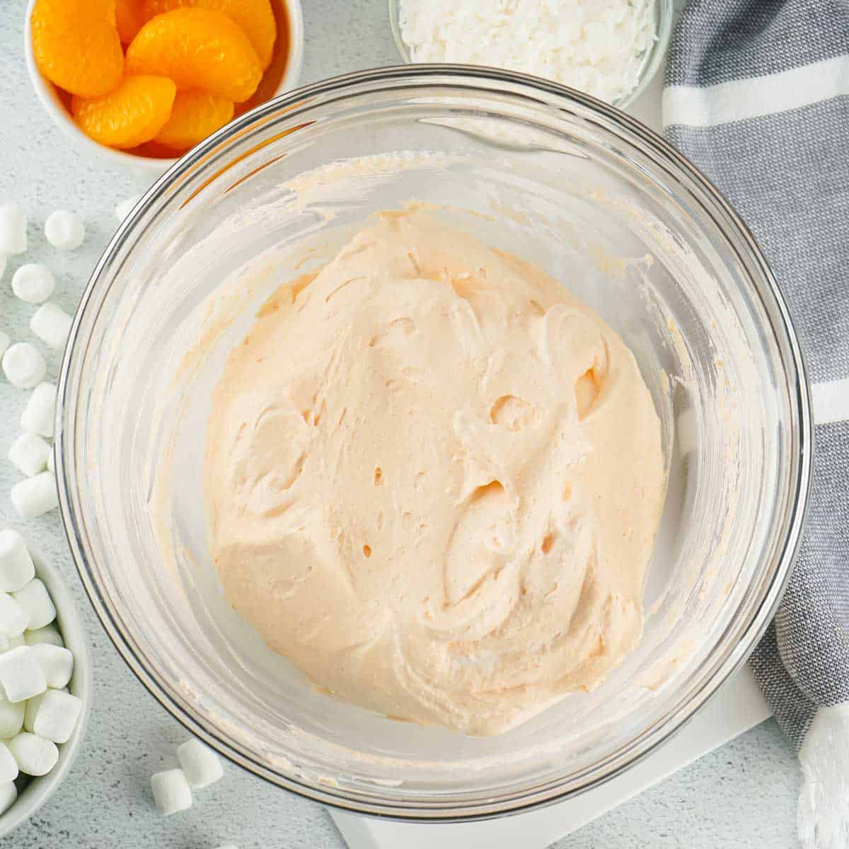 mixed whipped cream and orange jello mis in glass bowl