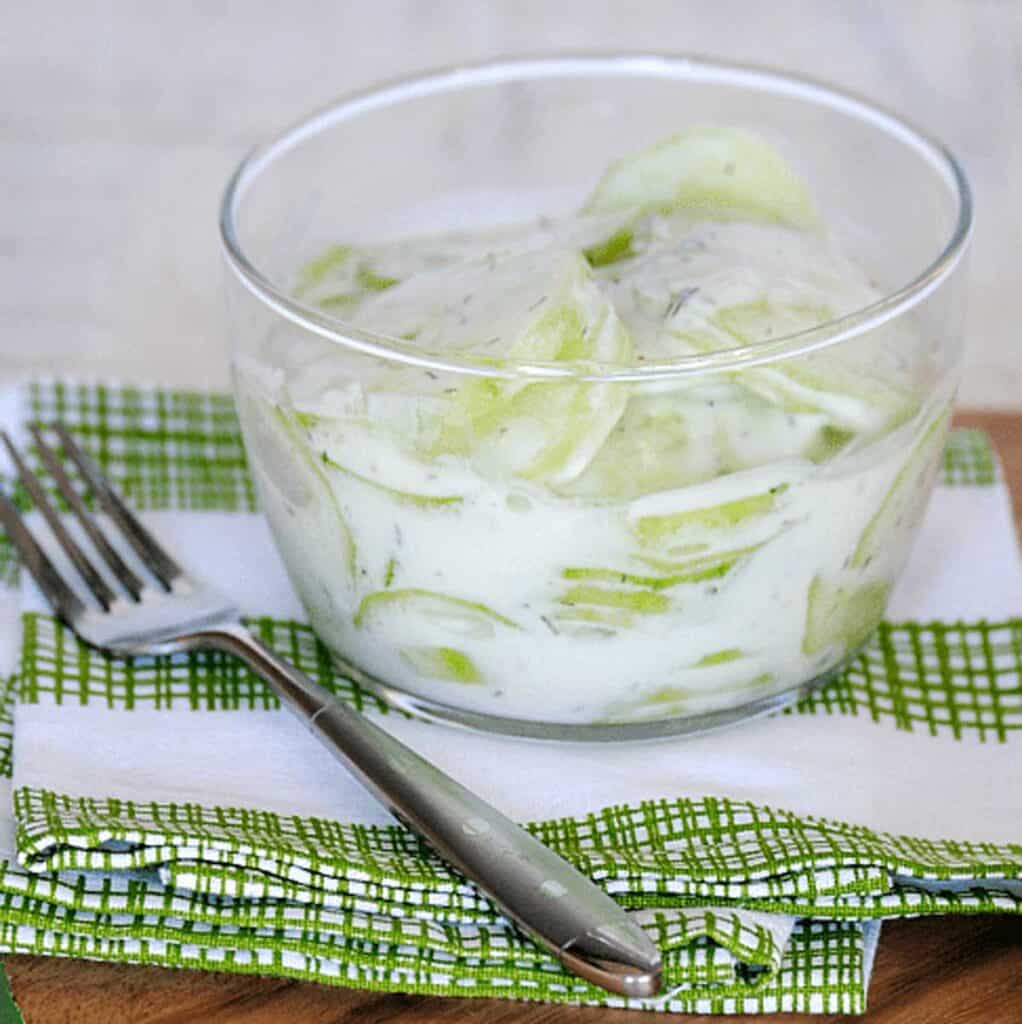 creamy cucumber salad with sour cream in a glass bowl