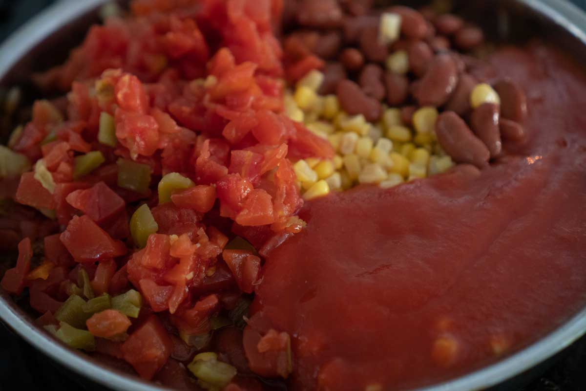 adding frito pie ingredients to skillet