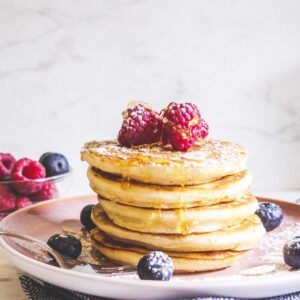 stack of light and fluffy pancakes topped with berries
