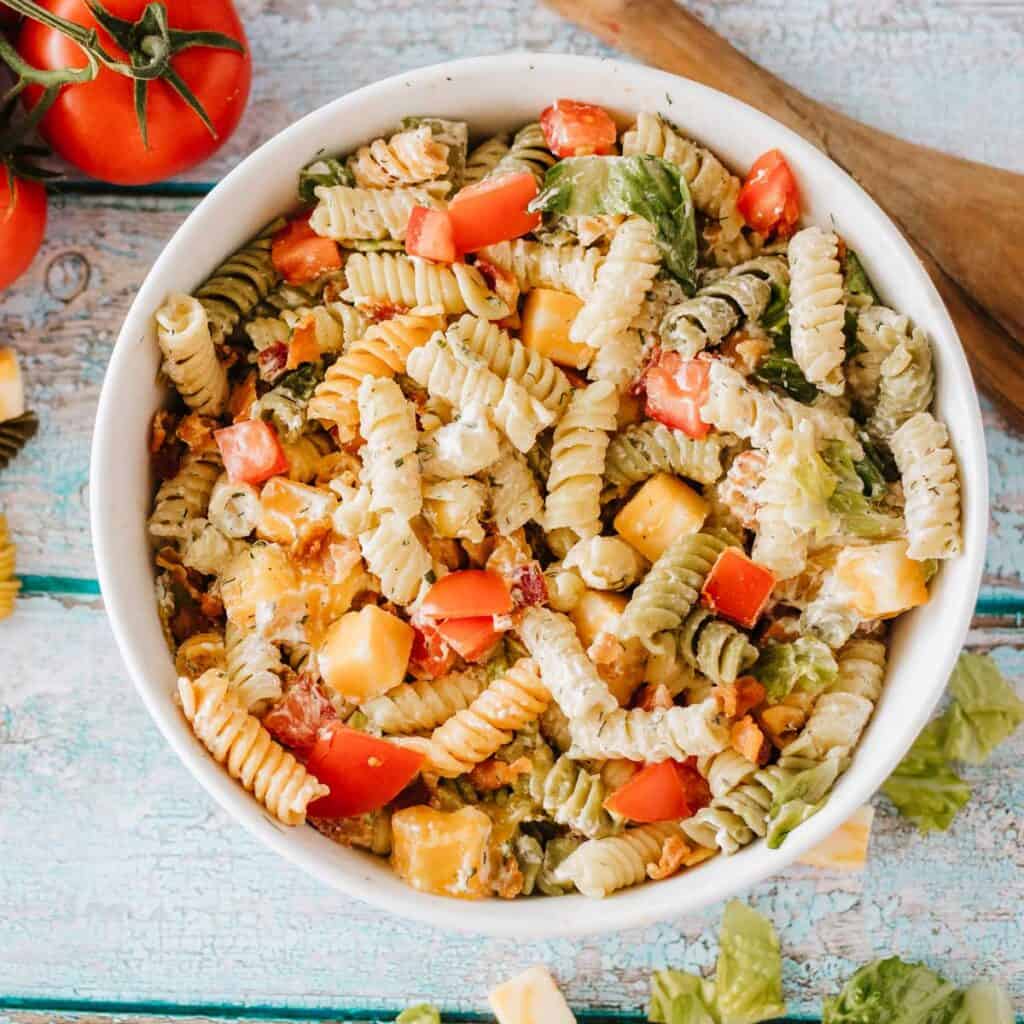 overhead view of white bowl with BLT pasta salad on wood counter