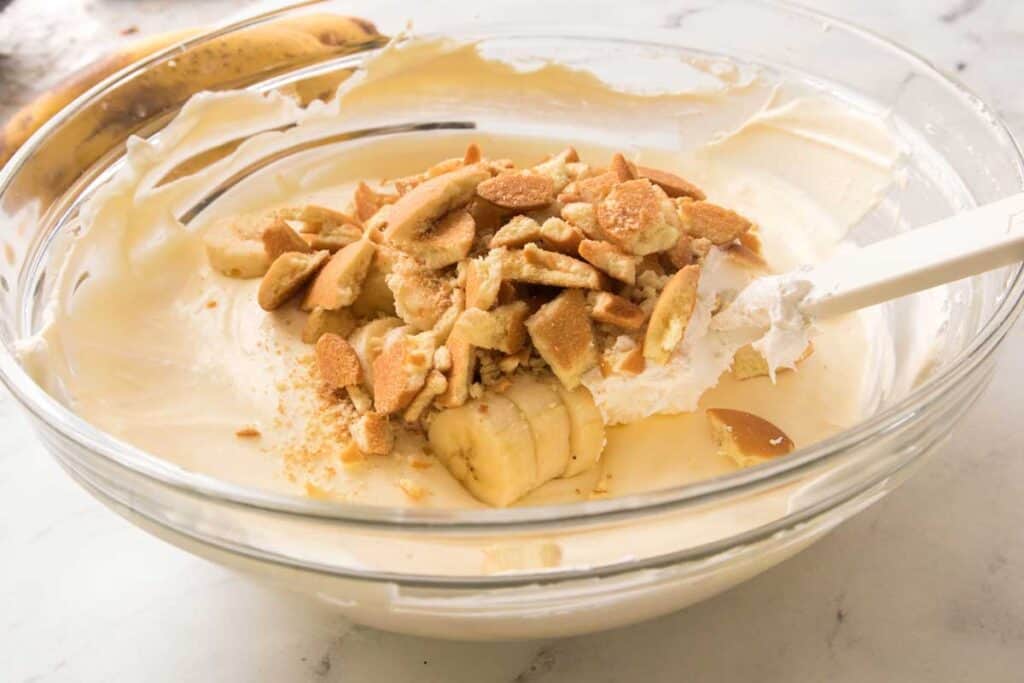 glass bowl with banana pudding ingredients being mixed together