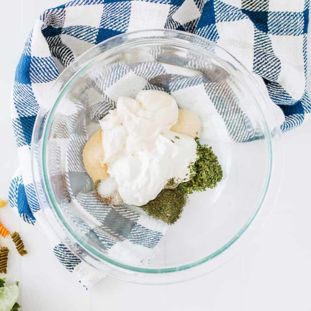 glass bowl with pasta salad dressing ingredients before mixing