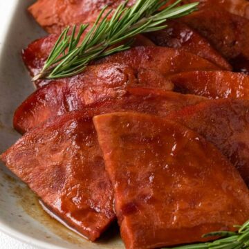 sliced glazed ham with rosemary sprig