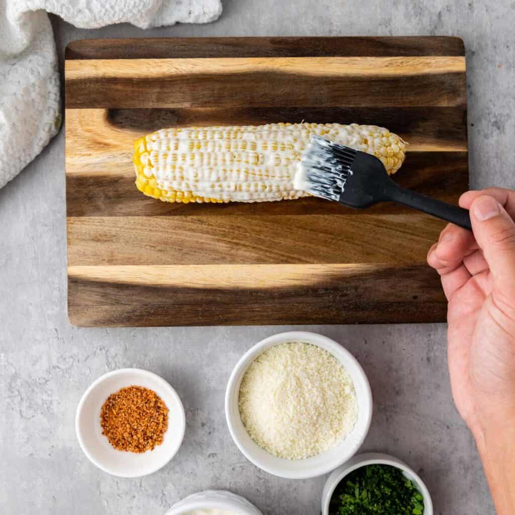 brushing mayonnaise on corn cob