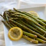 slow cooker asparagus on white plate with lemon slices