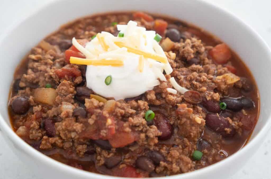 white bowl with stovetop chili topped with sour cream