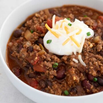 white bowl with stovetop chili topped with sour cream, cheese, and green onion