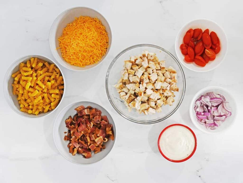 chicken bacon ranch pasta salad ingredients in bowls on countertop