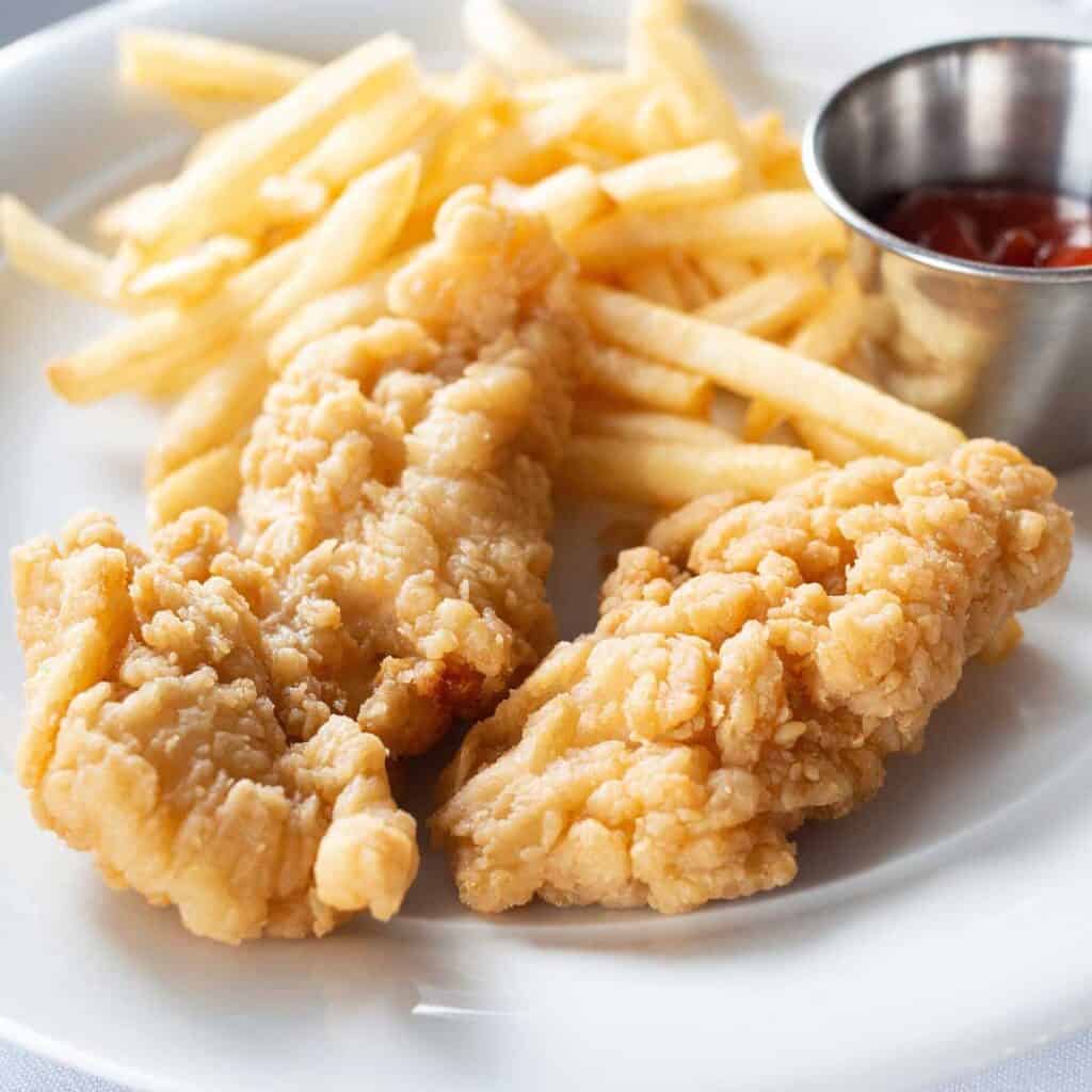 chicken tenders and fries on white plate