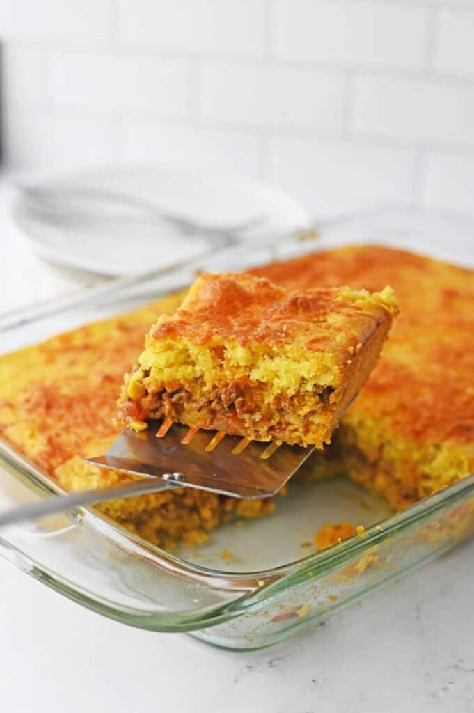 spatula lifting piece of cornbread casserole out of pan