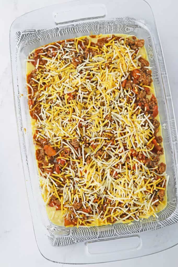 cornbread batter with ground beef mixture and cheese on top