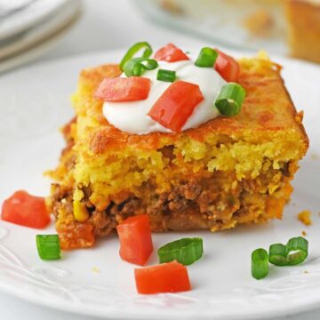 serving of cornbread casserole on white plate with green onion and bell pepper