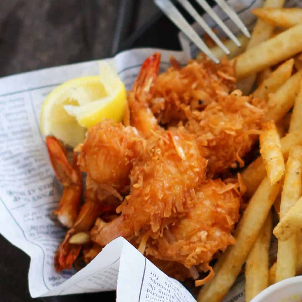 close up of coconut shrimp and fries with lemon wedge