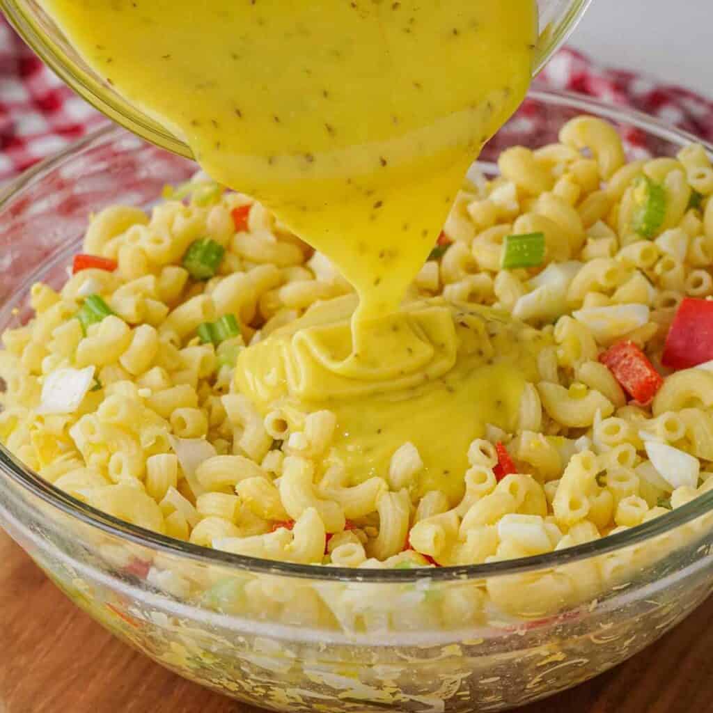 pouring dressing over Amish macaroni salad