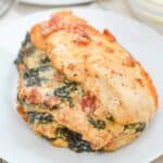 chicken breast stuffed with spinach, cheese, and bacon on white plate