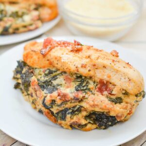 spinach and cheese stuffed chicken breast with bacon on white plate