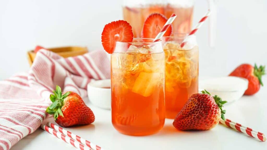 two glasses of strawberry sweet tea with napkin and straws
