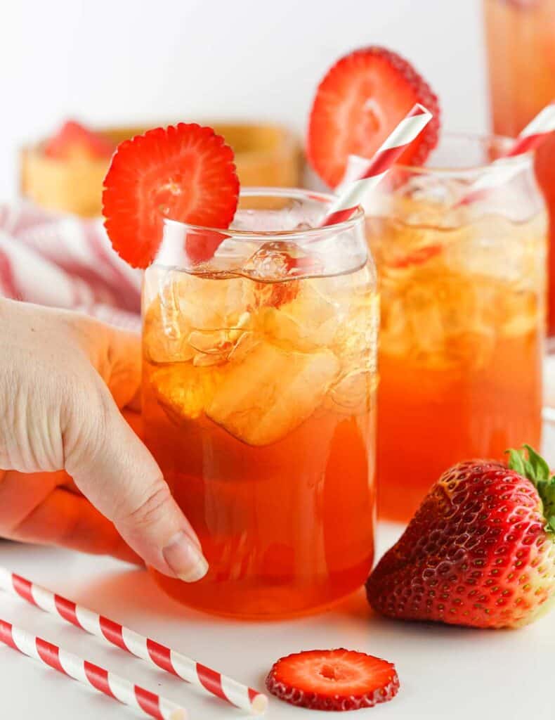 hand holding glass of strawberry sweet tea