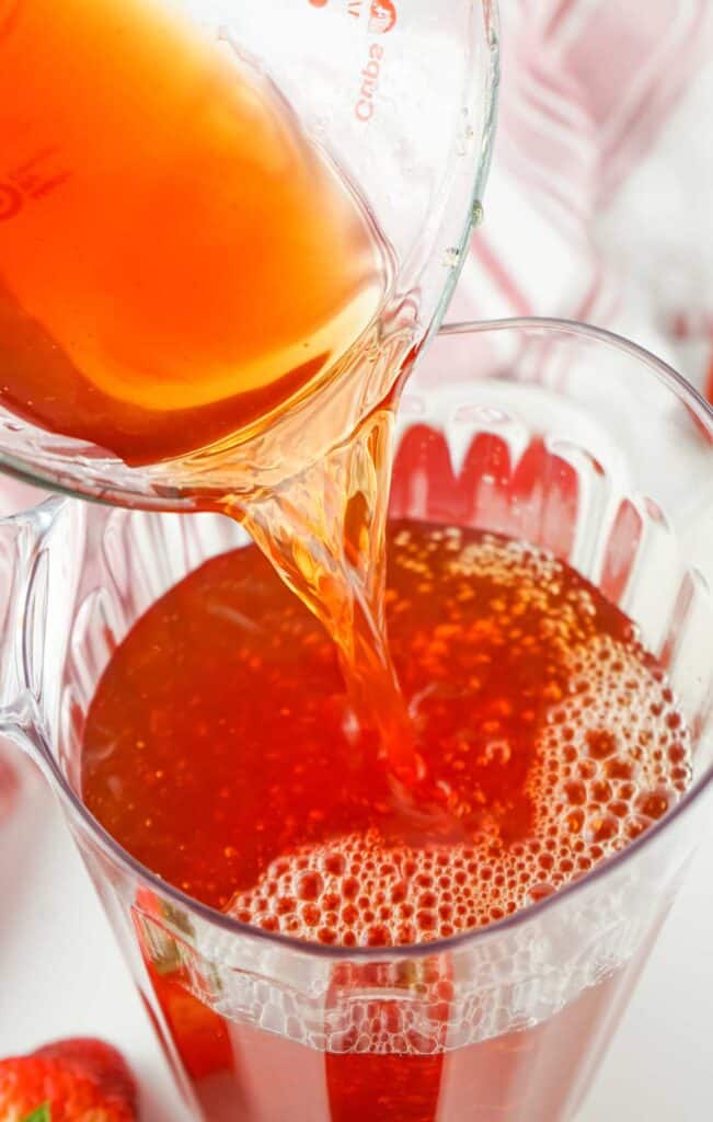 pouring strawberry syrup into sweet tea