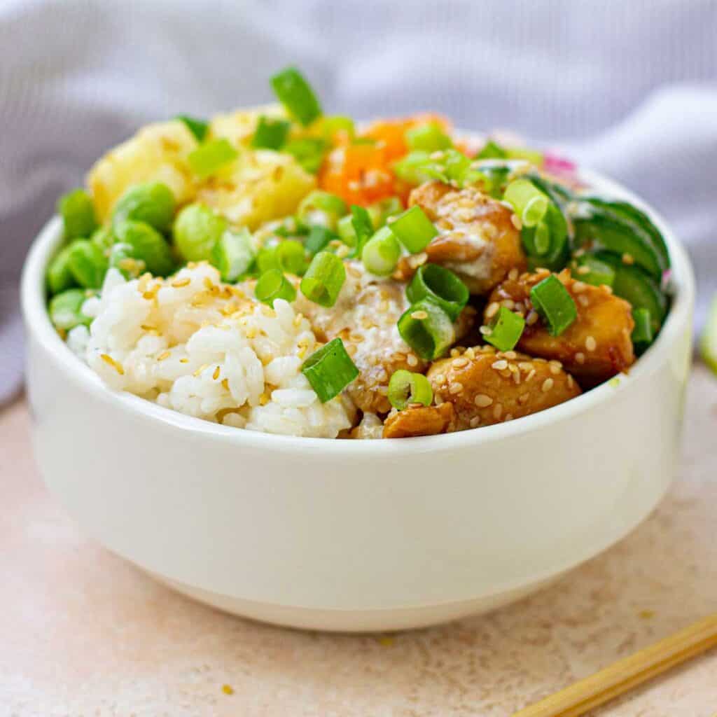 white bowl with rice, vegetables, and teriyaki chicken