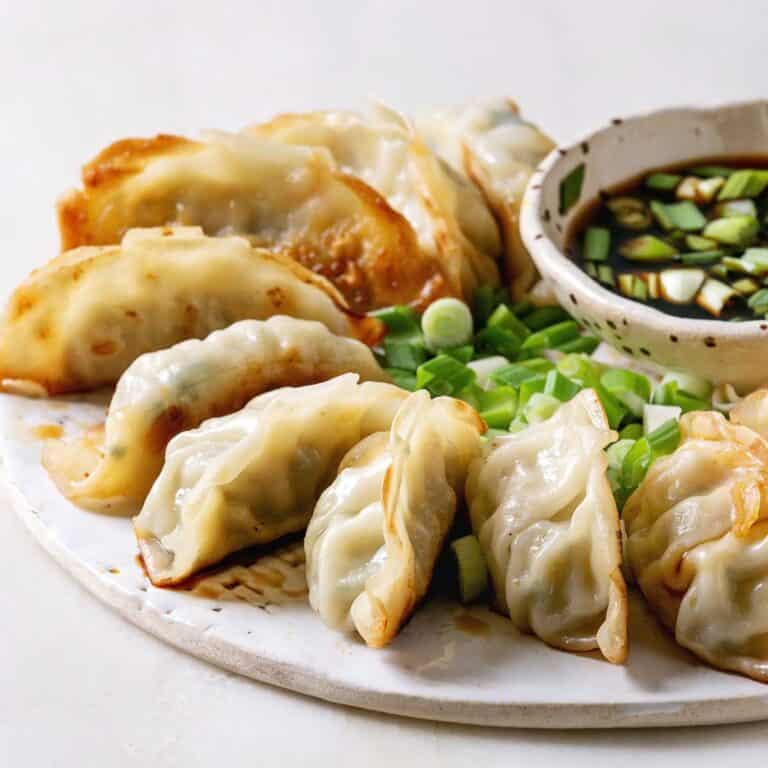 potstickers on plate with chopped green onion and soy sauce