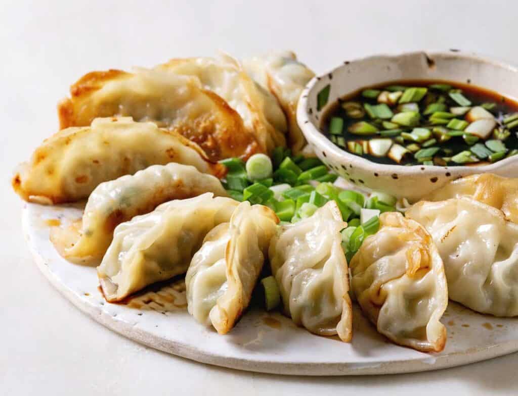 potstickers and soy sauce on plate with chopped green onion