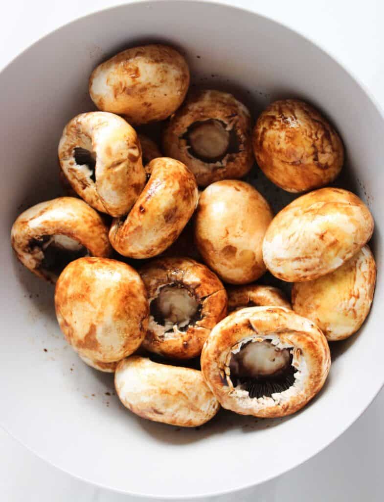 marinating mushroom caps in white bowl