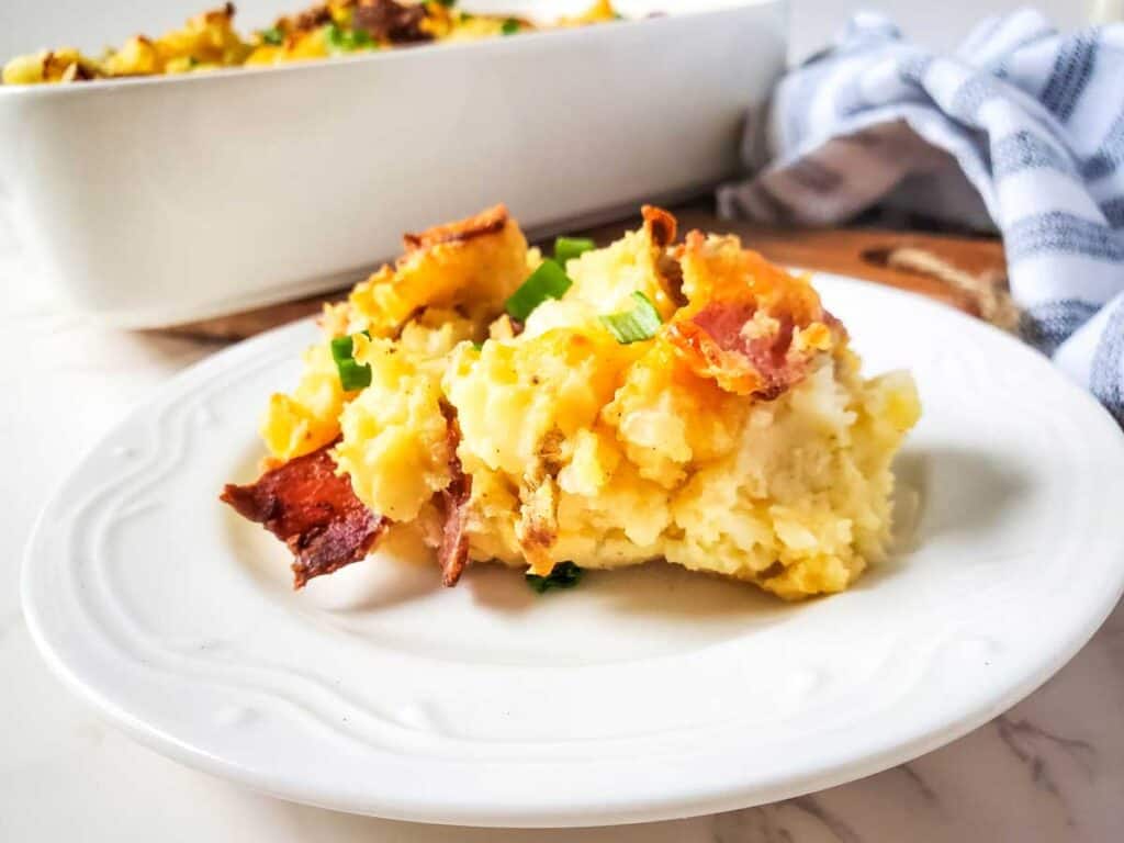 close up of twice baked potato casserole on white plate