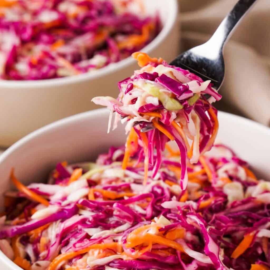 fork with coleslaw on it over bowl