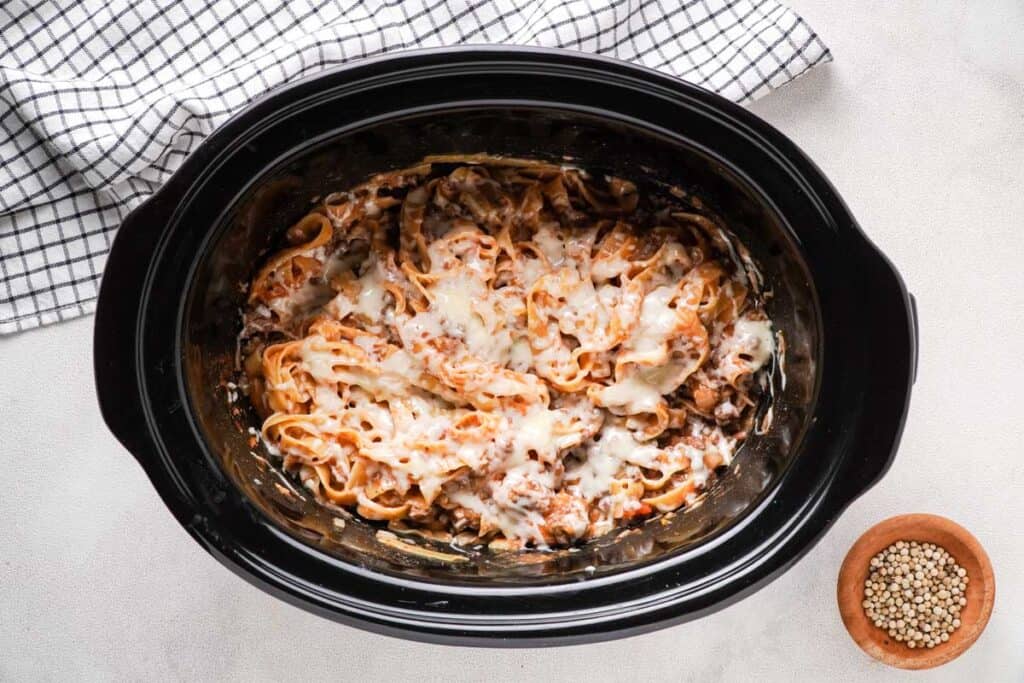slow cooker with ground beef and noodles topped with cheese