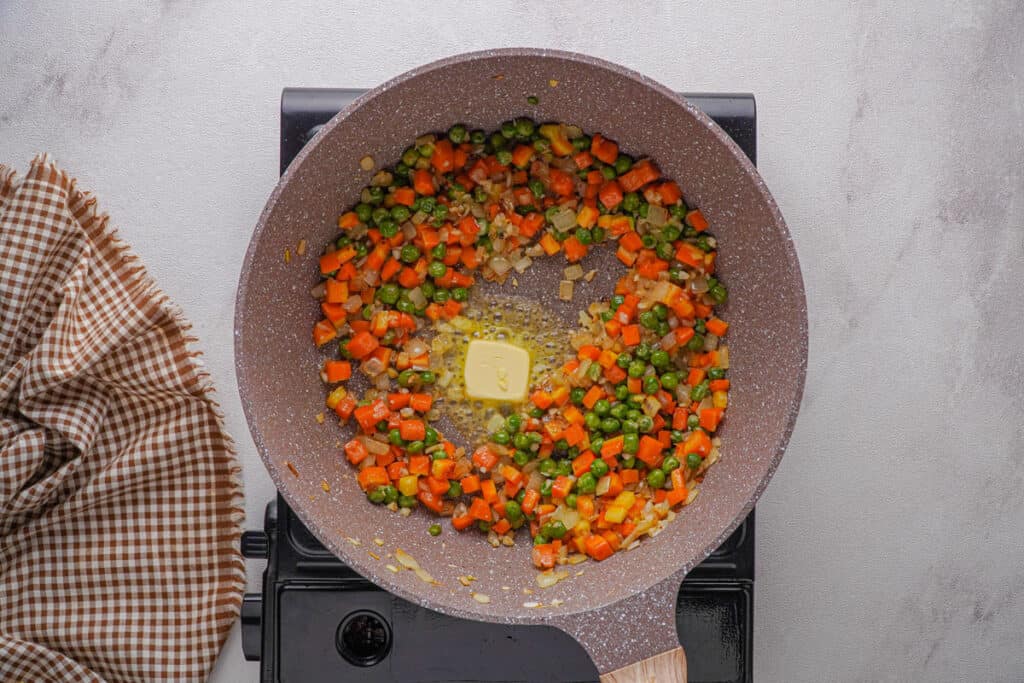 sautéing vegetables in butter in skillet for fried rice