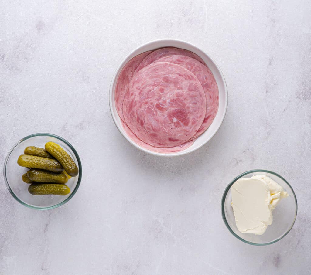 ham and pickle roll up ingredients in bowls on marble counter