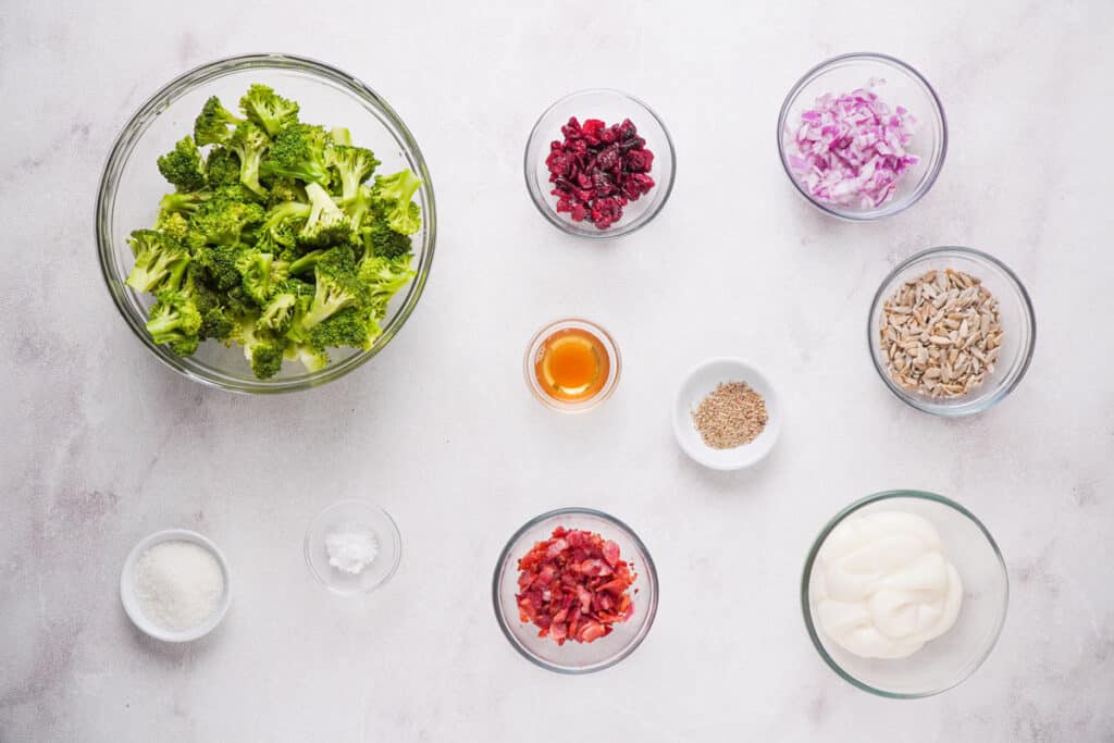 broccoli salad ingredients in glass bowls on countertop