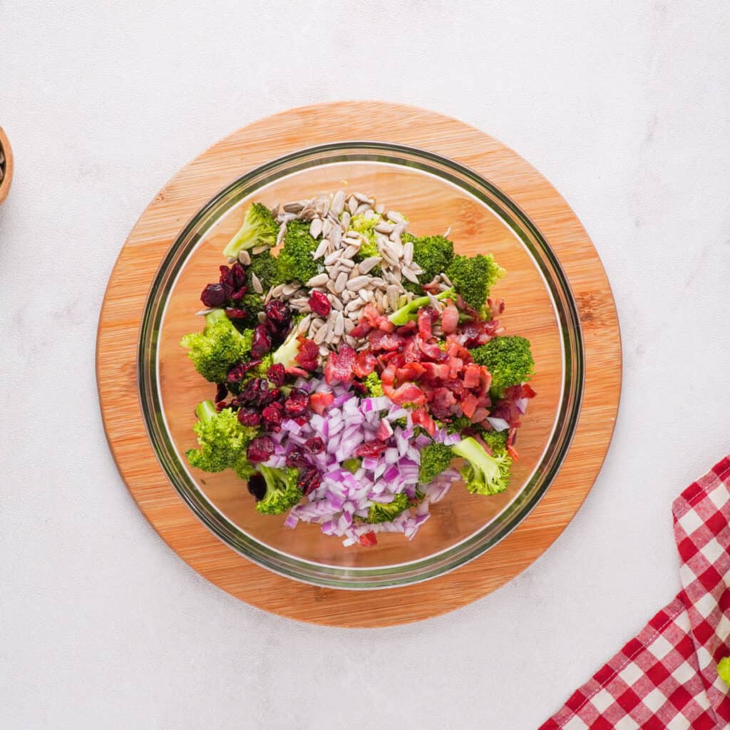 overhead view of broccoli salad ingredients together in glass bowl