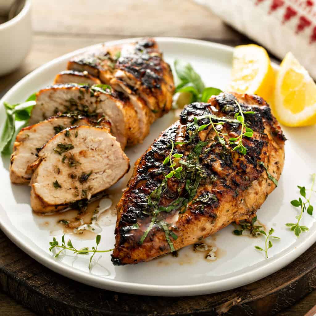 grilled chicken breast on white plate with one sliced