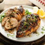 two grilled chicken breasts on white plate