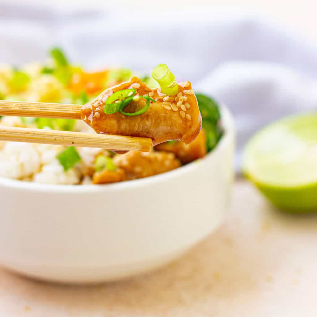 chopstick holding piece of teriyaki chicken